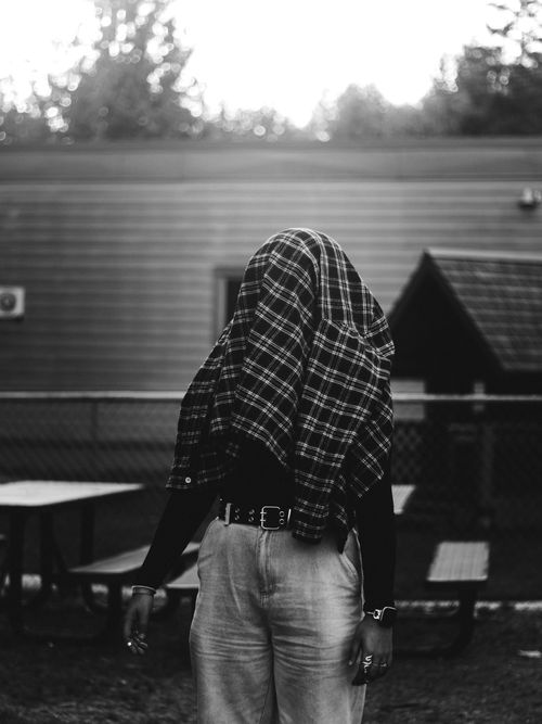 Free Black and white photo of person with a flannel shirt over their head in a backyard setting. Stock Photo