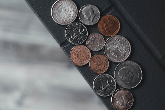 A flat lay image showcasing a diverse array of international coins laid on a textured surface.