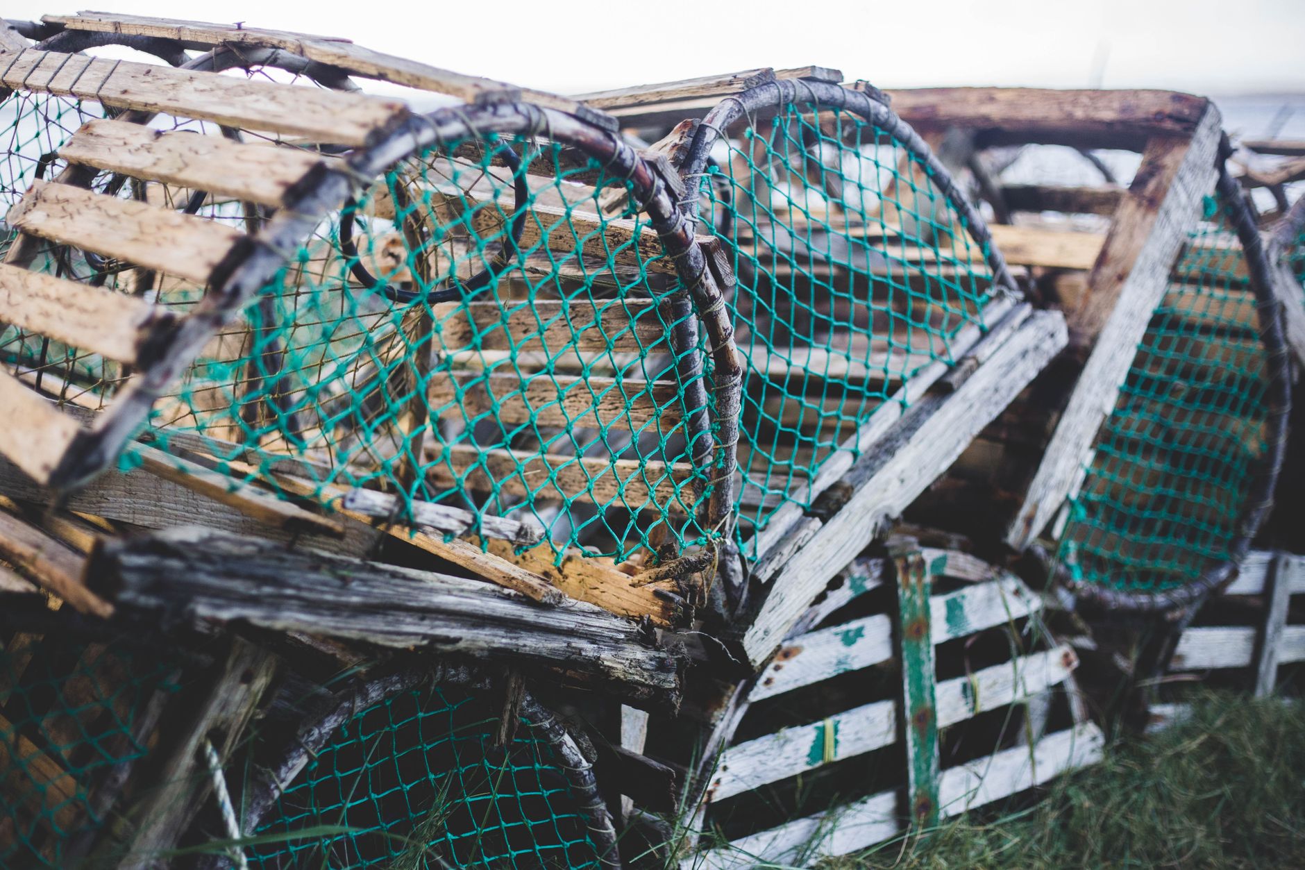 Close-up of old wooden lobster traps stacked outdoors with green nets.
