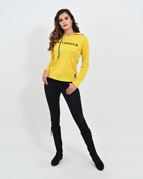 Free Stylish woman posing in a yellow hoodie and black pants on a white studio background. Stock Photo