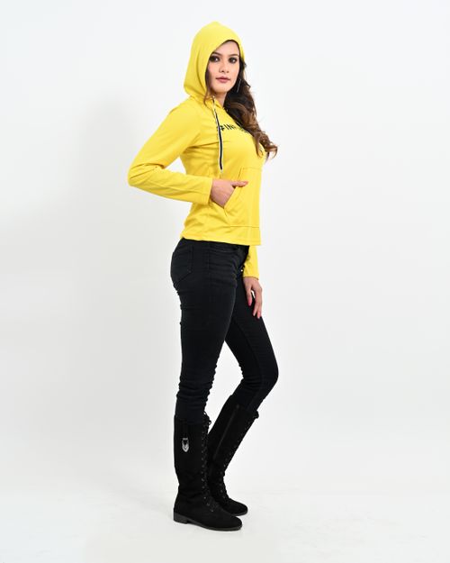Free Fashionable woman wearing a yellow hoodie and black boots posing in a studio setting with a white background. Stock Photo