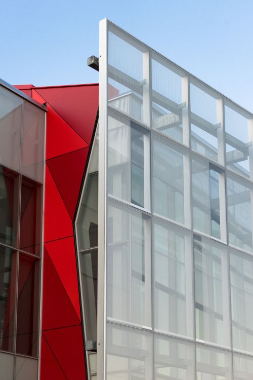 Free Dynamic modern building facade featuring bold geometric shapes and contrasting colors. Stock Photo