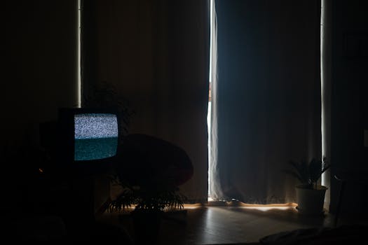 A dimly lit living room with static on the TV and curtains drawn, creating a moody atmosphere.