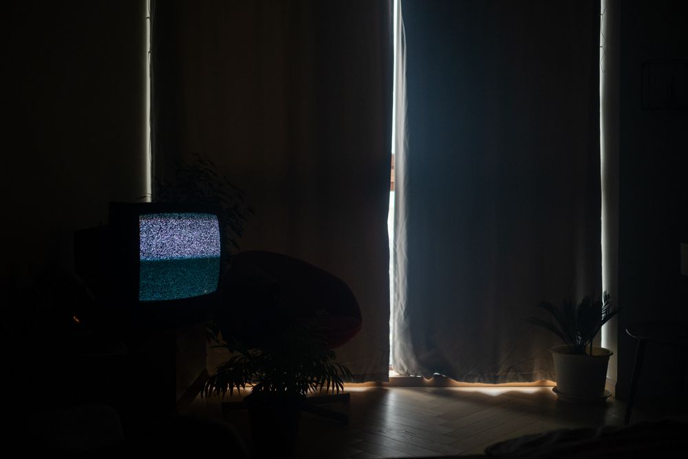 A television glowing with static in a dark living room at night