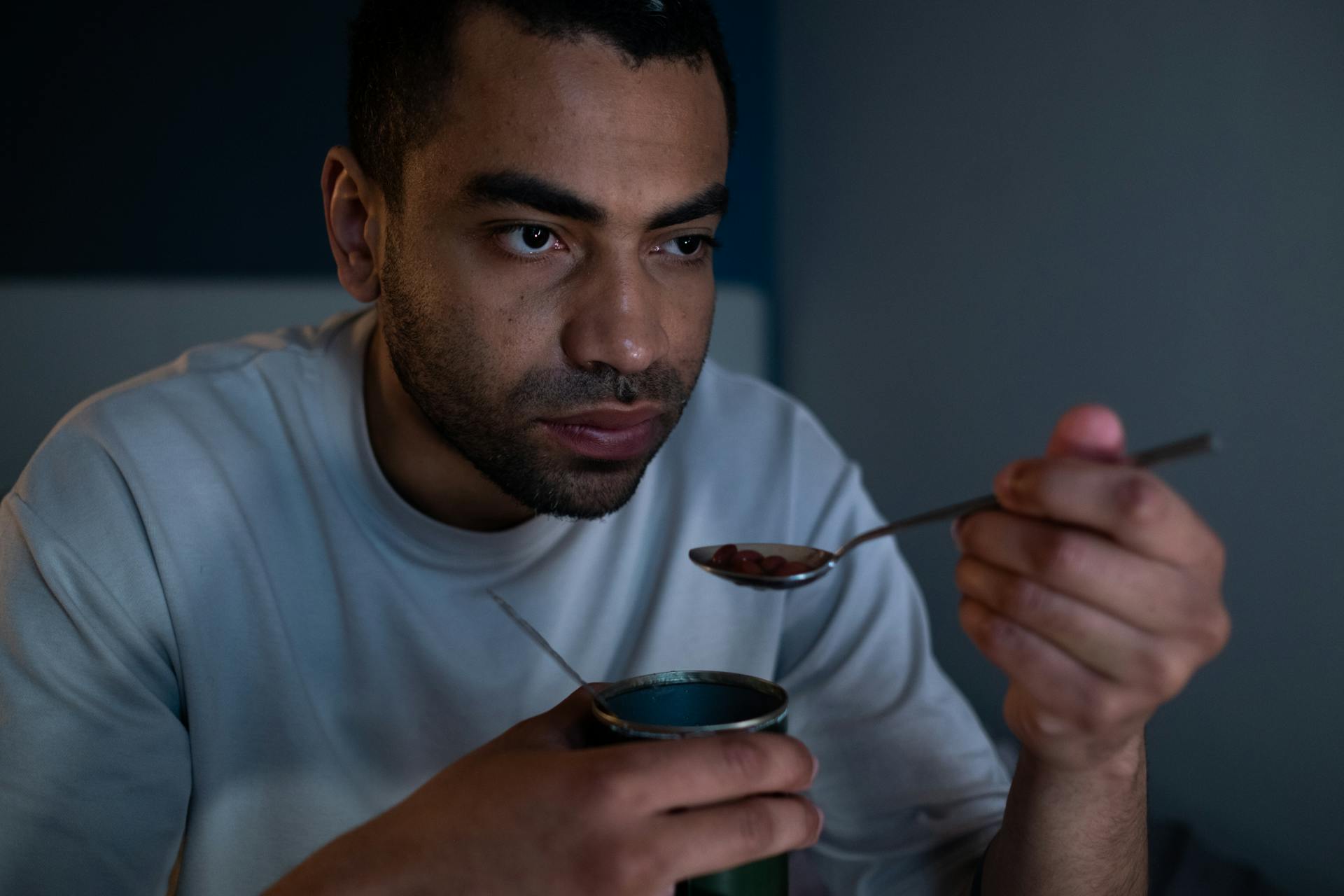 Man Holding a Spoon Eating Canned Food