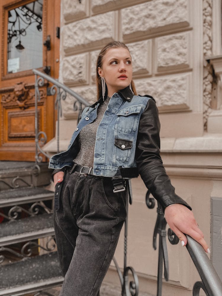 Blond Woman Wearing Jeans And Leather Jacket Standing At Entrance To Old Building