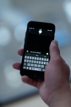 Close-up of a person texting on a smartphone indoors with a blurred background.