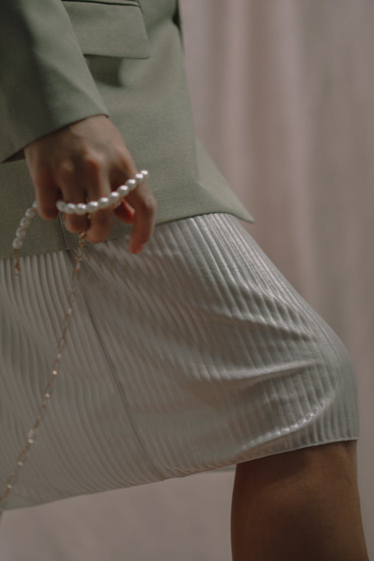 A Woman In Green Blazer Holding A String Of Pearls