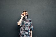 A Man Wearing a Bandana and Printed Top Covering Eye