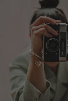 Close-up of a woman holding a vintage camera, showcasing intricate bracelets.