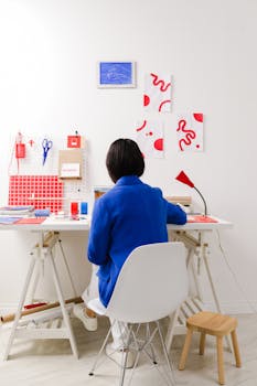Woman in blue jacket working in a bright, minimalist office space.