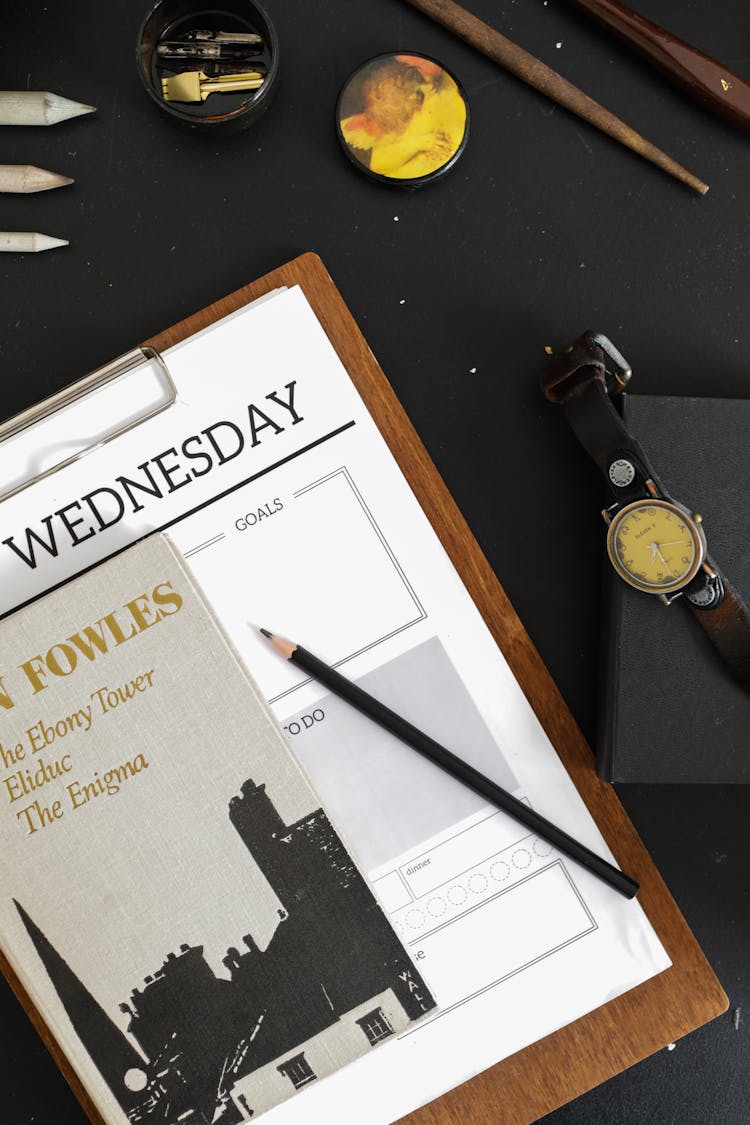 A Pencil On A Planner Beside A Box With Wristwatch