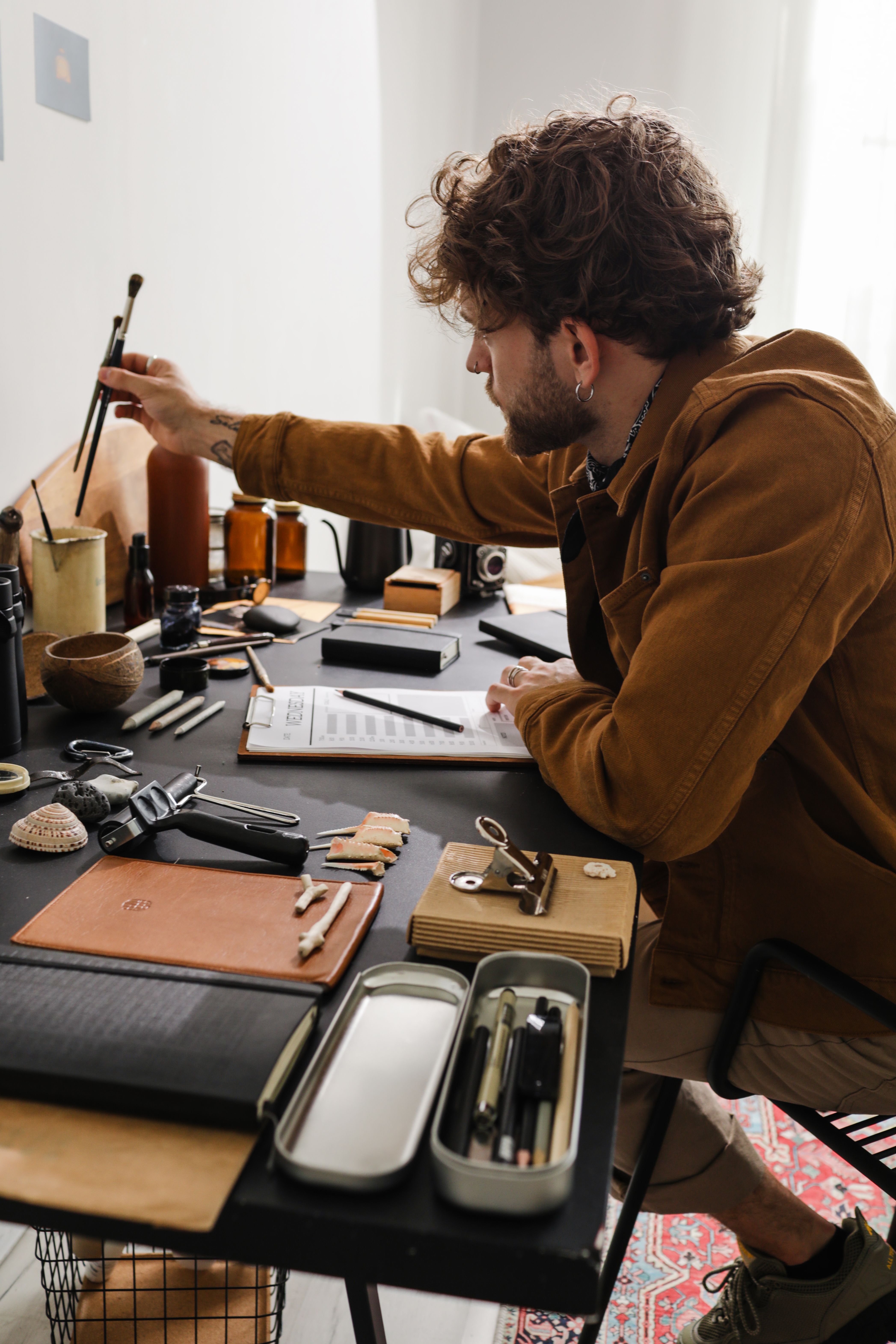 The Studio Overshirt in washed clay cotton, worn by an artist in his studio