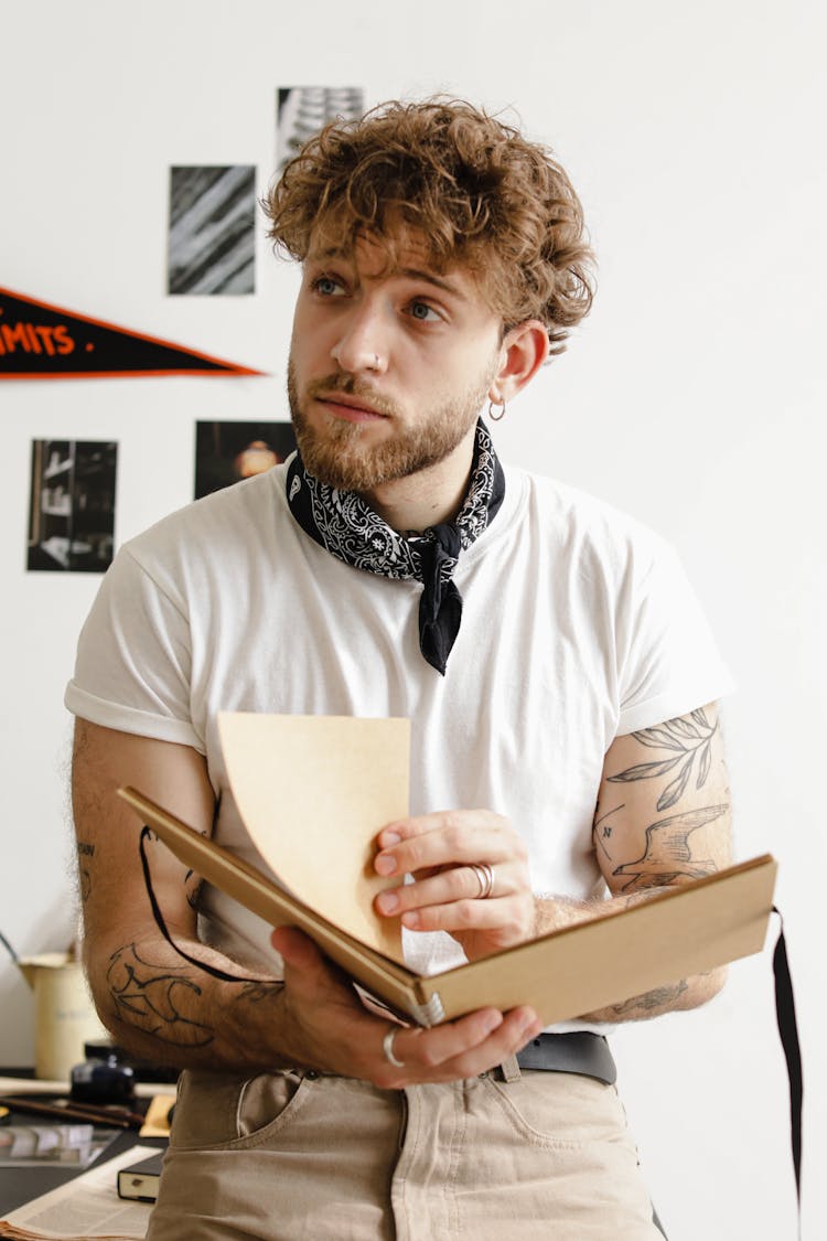 Man Turning The Pages Of Brown Notebook