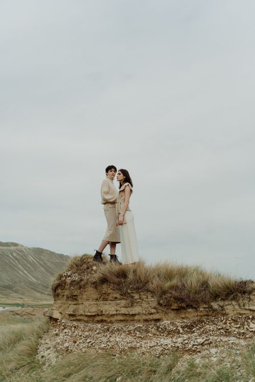 Free Two women in stylish outfits standing on a scenic cliffside under an overcast sky. Stock Photo