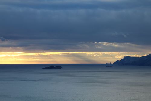 Free A serene seascape at twilight with dramatic cloudy skies and distant islands. Stock Photo