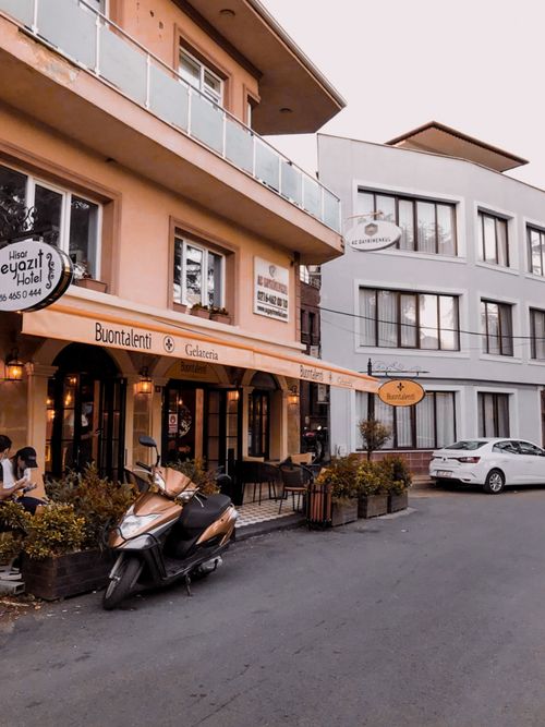 Free A picturesque street view with a cozy cafe and parked scooter. Stock Photo