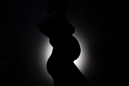 Silhouette of a Pregnant Woman Standing on a Black Background