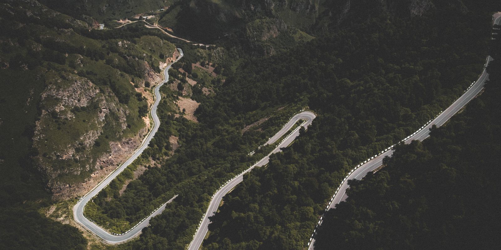 A winding mountain road cutting through lush forested highlands