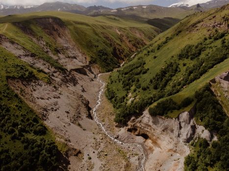 Experience the breathtaking aerial view of a rugged mountain valley featuring lush green landscapes and deep canyons.