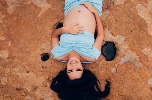 Free Pregnant Woman Lying on Brown Surface Stock Photo