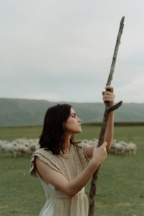 A Woman Holding a Thick Stick While Looking Afar