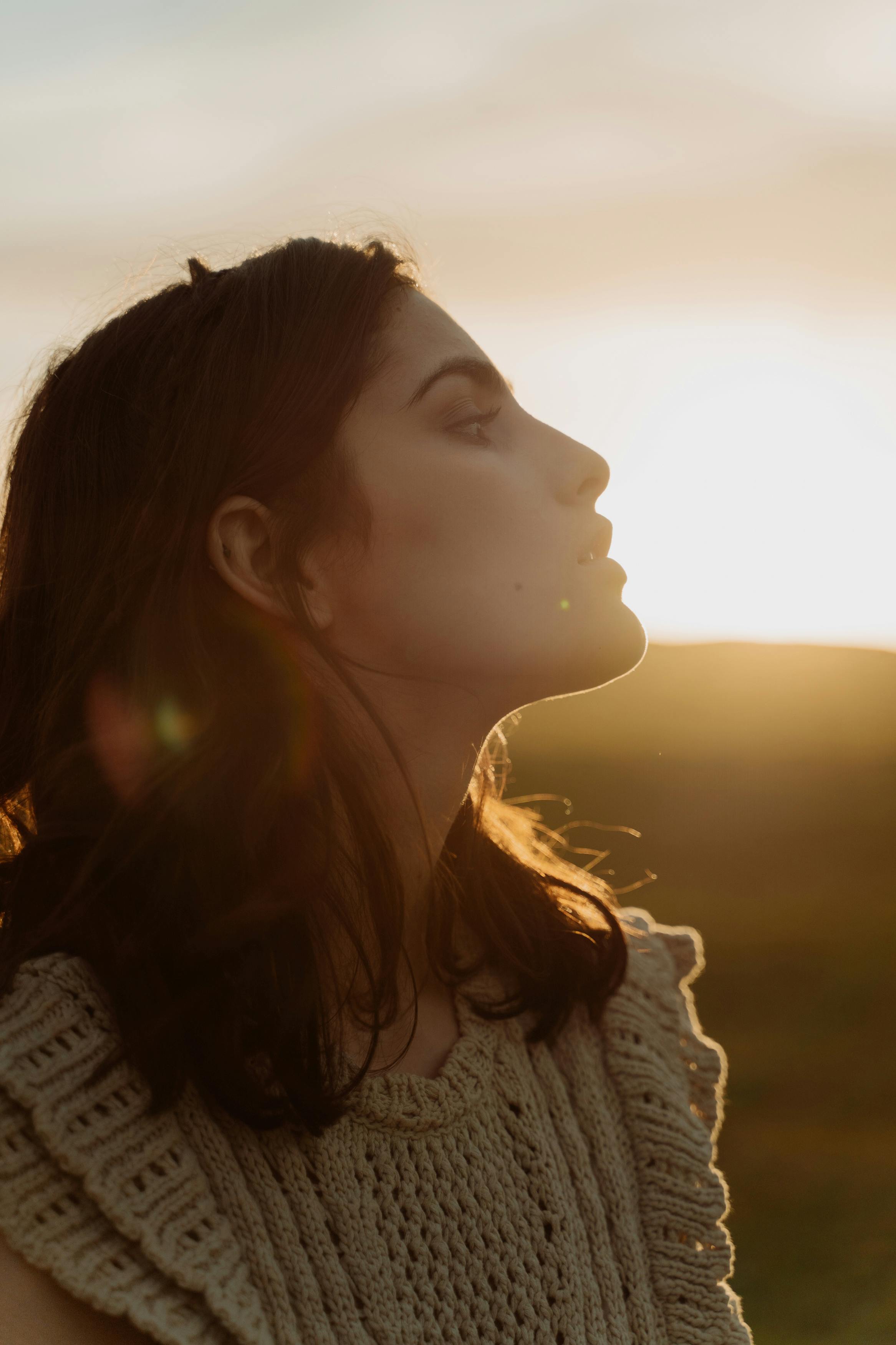 A serene side profile portrait of a woman at sunset highlighting natural beauty and tranquility.