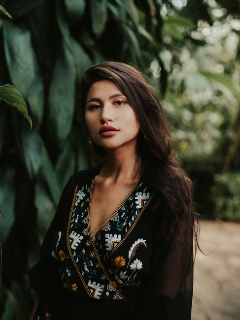 Portrait of a stunning woman in nature with vibrant green leaves.