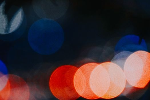 Blurred bokeh lights in red and blue creating a vibrant abstract pattern against a dark backdrop.