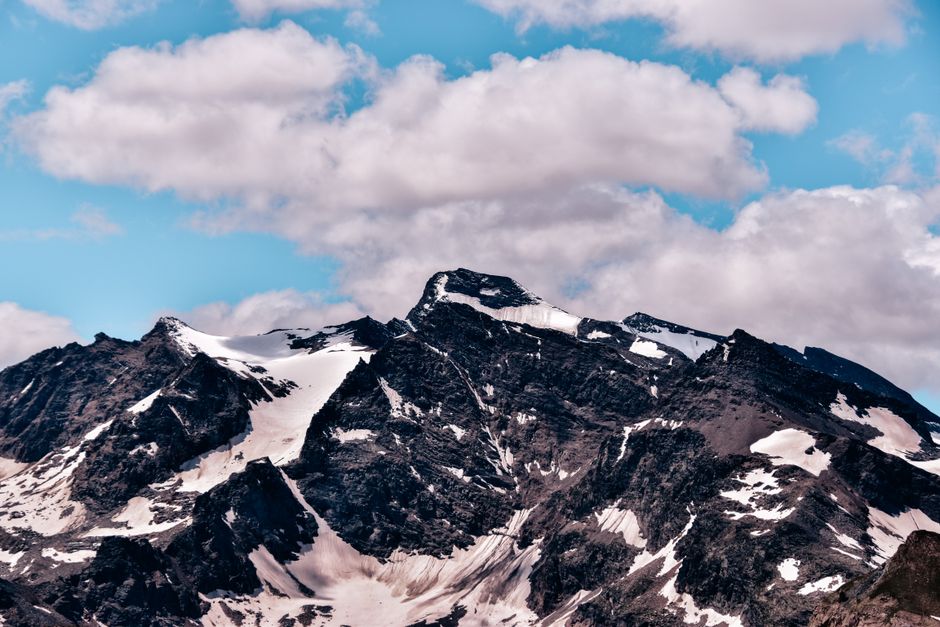 Snow-covered mountain peaks under a blue sky with scattered clouds, capturing the essence of winter.