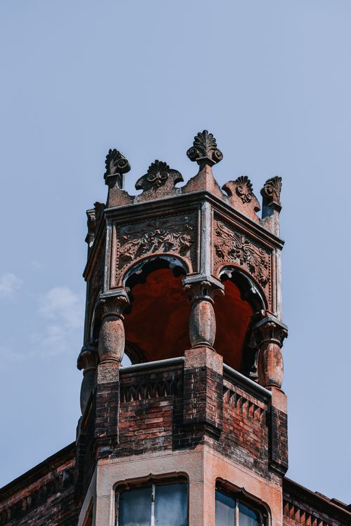Free Close-up of a historic gothic tower with intricate ornamental details against a clear blue sky. Stock Photo