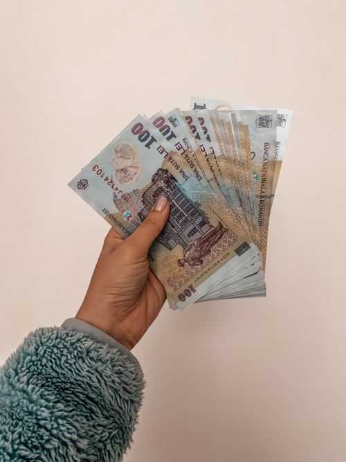 Free A person holding a fan of Romanian banknotes against a neutral backdrop, showcasing economy and finance. Stock Photo