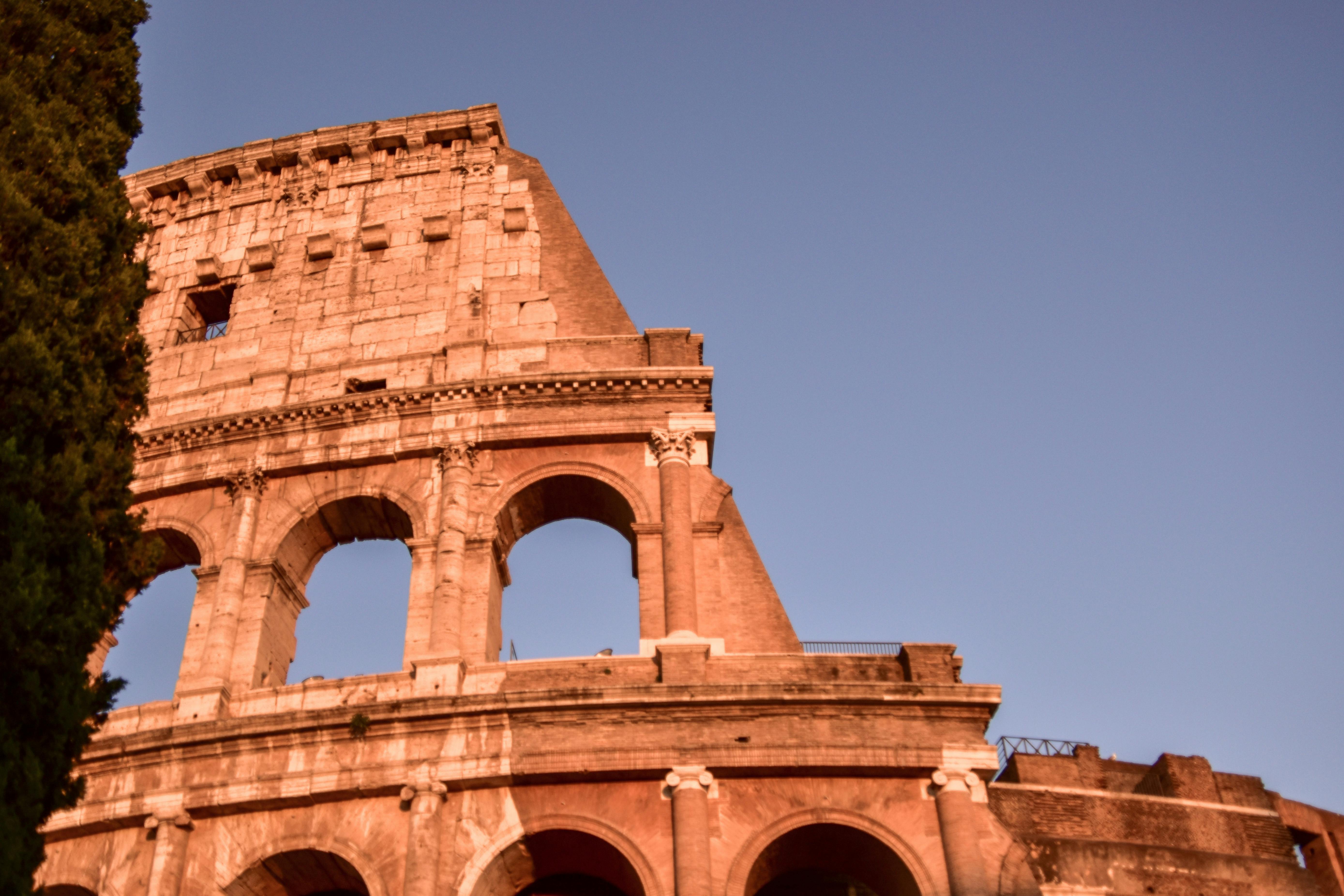 Free The Colosseum's arches glow warmly under the setting sun in Rome, Italy. Stock Photo