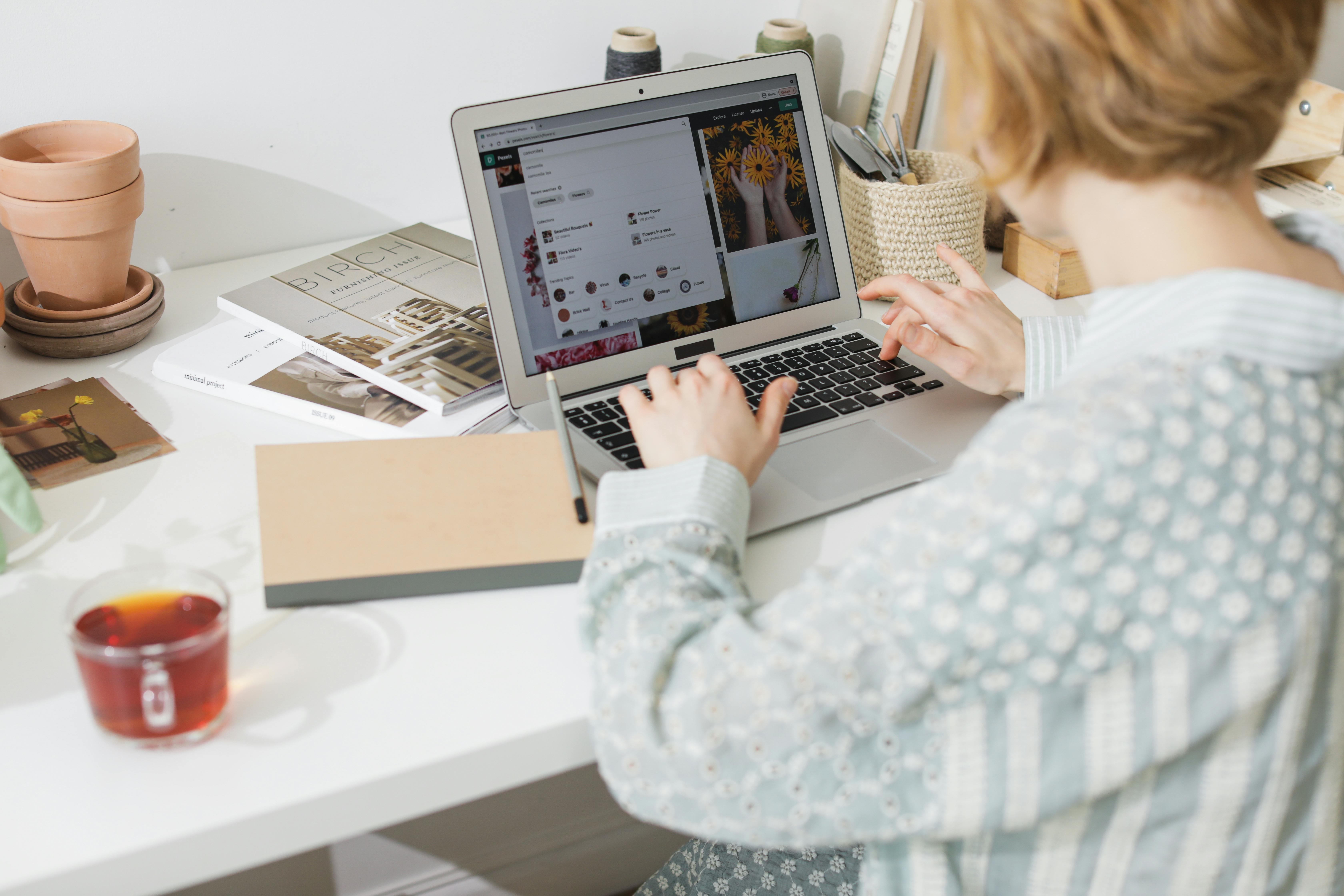 Woman working on laptop in light-filled creative home workspace. Cozy and productive setting.