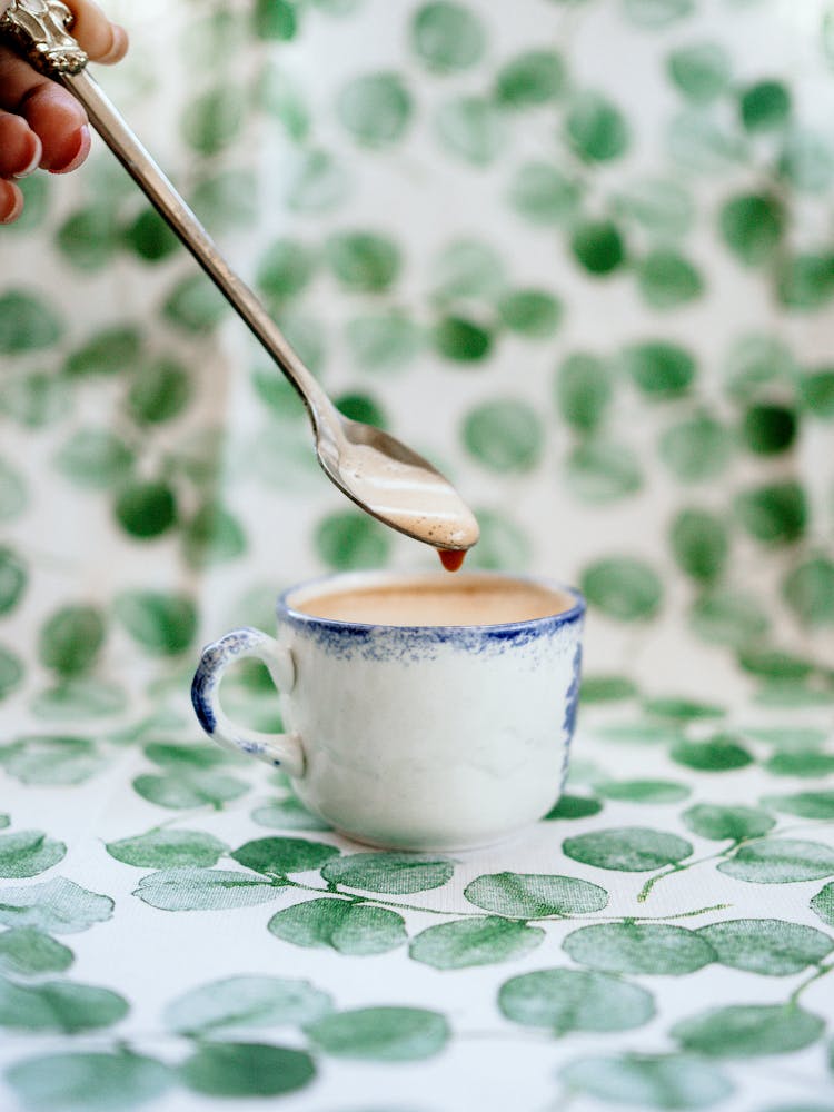 A Hand Holding A Teaspoon With Coffee