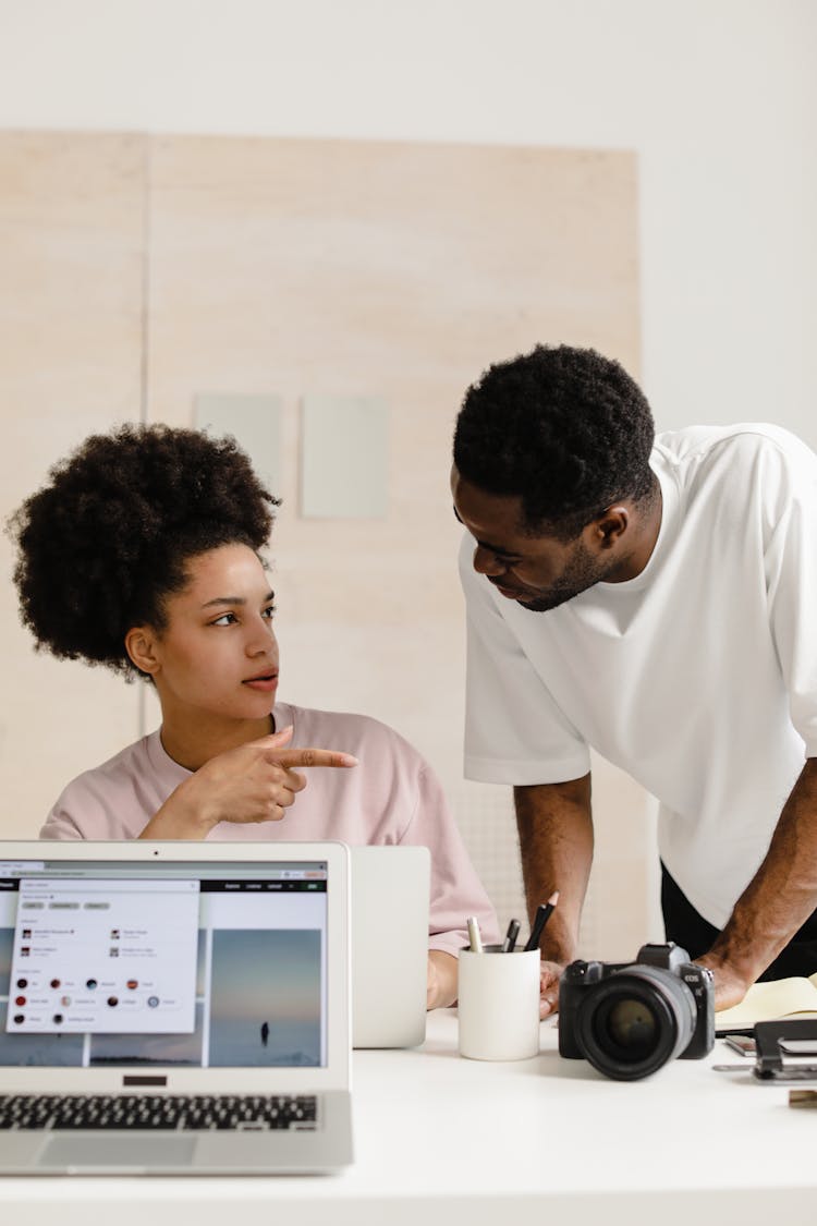 Man Talking To The Woman Sitting In Front Of The Laptop 