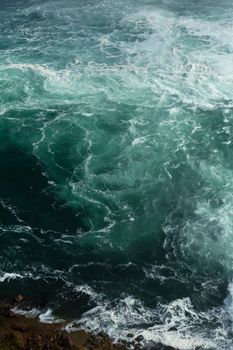 Vibrant turquoise rapids over rocks at Niagara Falls, capturing nature's raw power and beauty.
