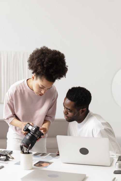 Free Photographers collaborate on project, reviewing shots on DSLR camera in a studio setting. Stock Photo