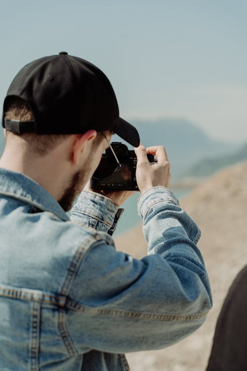 Free Man with a Black Cap Using a Camera to Take a Picture Stock Photo
