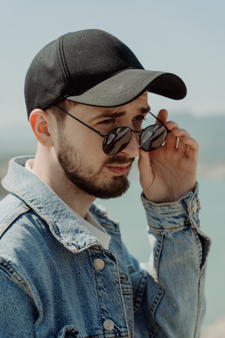 Portrait Of A Man In A Denim Jacket Touching His Sunglasses