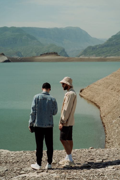 Free Two men standing near a serene mountain lake, surrounded by picturesque hills. Stock Photo