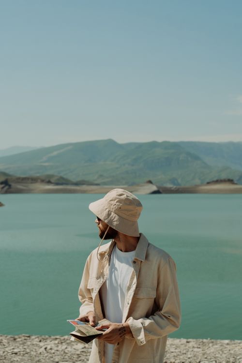 Free A man in beige attire enjoys a scenic lakeside view, capturing the essence of travel and adventure. Stock Photo