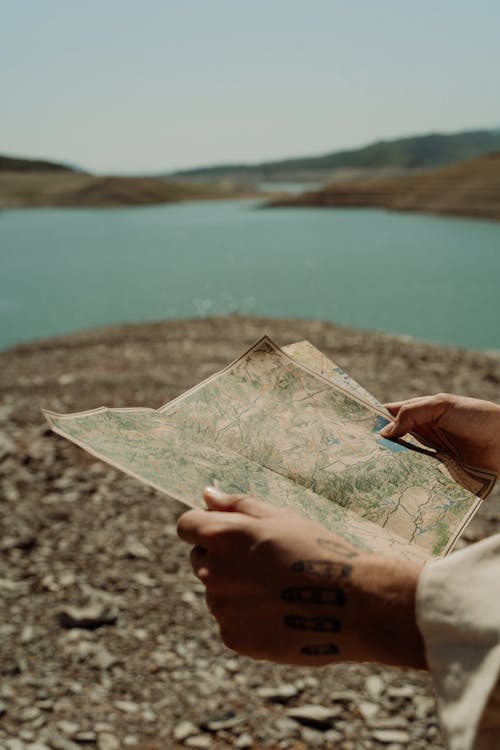 Closeup of a Person Holding a Vintage Map by a Lake