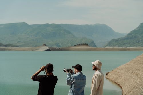 Free Three photographers capturing a stunning mountain lake landscape outdoors. Stock Photo