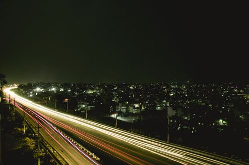Free Nighttime highway with light trail effect, overlooking a bustling cityscape. Stock Photo
