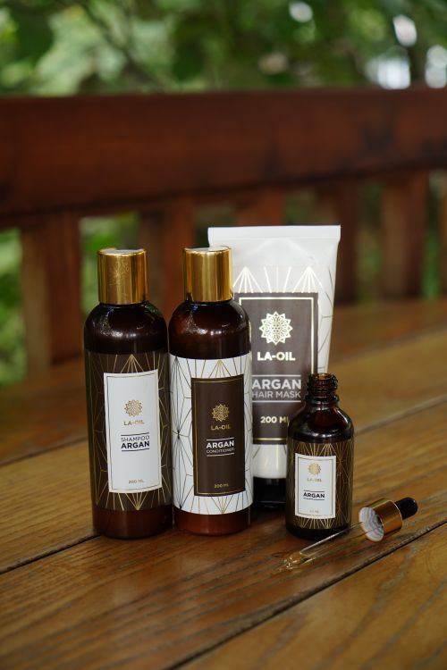 Hair oils and grooming products arranged on a wooden surface