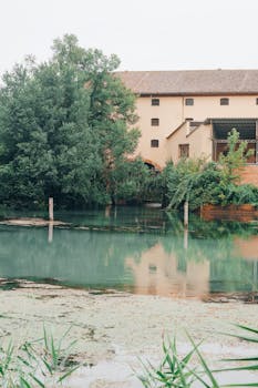 A tranquil scene of an abandoned building reflecting on a calm river in Casier, Veneto, Italy.