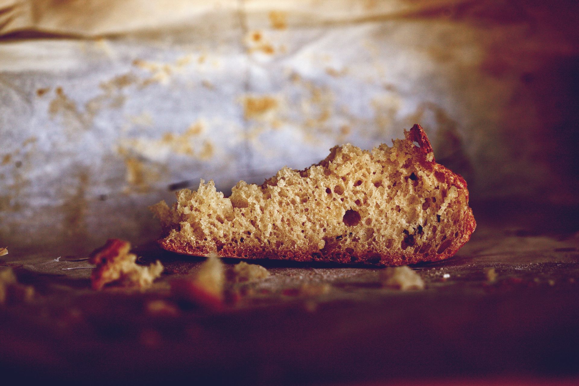 Close-up of rustic brown bread crumb on textured baking paper, evoking warmth and simplicity.