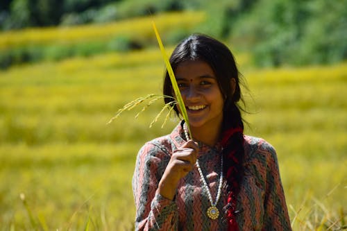 A Woman Smiling at Camera While Holding a Wheat Grass