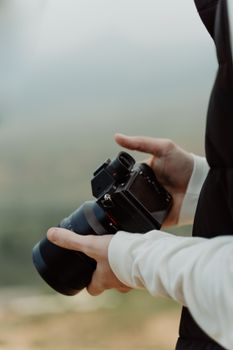 Hands holding a DSLR camera outdoors with a blurred background. Perfect for photography themes.